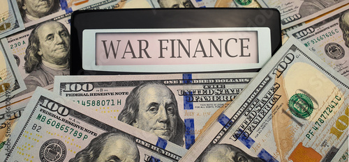 War finance. A calculator surrounded by 100 US dollar bills. Concept of militarization, increase in spending on weapons for defense, arming the army, training the military, fighting terrorism photo
