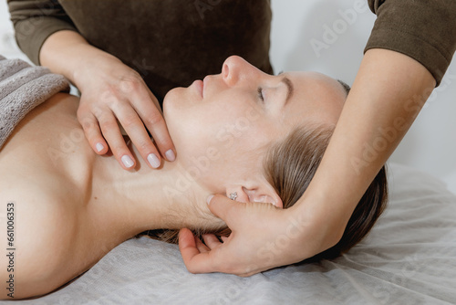 buccal facial and neck massage, close-up, cosmetologist makes woman a procedure on a massage table in a spa salon