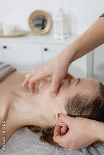 buccal facial massage, close-up, cosmetologist makes woman a procedure on a massage table in a spa salon