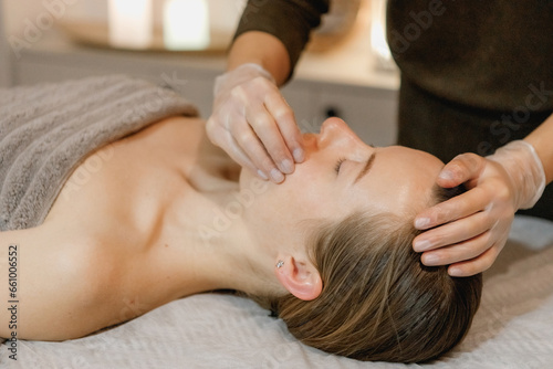 buccal facial massage, close-up, cosmetologist makes woman a procedure on a massage table in a spa salon photo