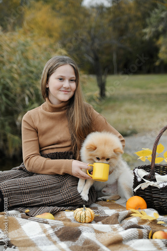 Beautiful teenager playing with her littele dog in autumn park, cozy autumn concept