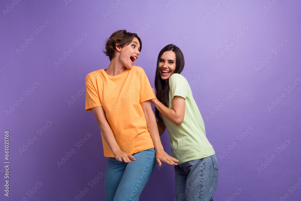 Photo of funny impressed ladies wear t-shirts dancing smiling having fun isolated violet color background