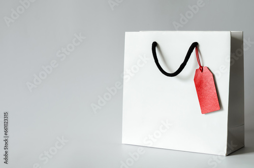 White shopping paper bag with red blank price tag on white background for Black Friday shopping sale concept.
