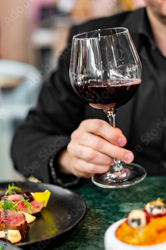 Young man hand holding a glass with red wine in a restaurant