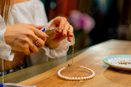 close-up a young beautiful girl makes jewelry with her own hands cuts the remnants of wire for a necklace with pliers craft production photo