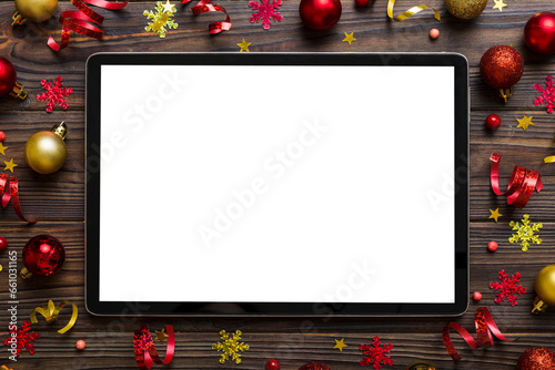 Christmas online shopping from home tablet pc with blank white display top view. Tablet with copy space on colored background with Christmas decorations balls,. Winter holidays sales background