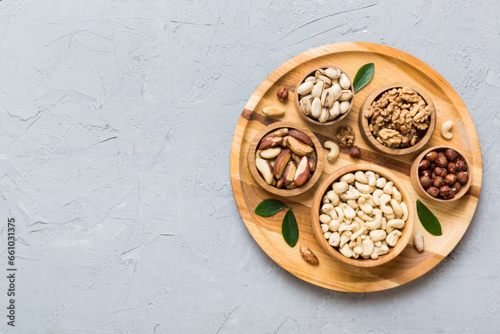 mixed nuts in wooden bowl. Mix of various nuts on colored background. pistachios, cashews, walnuts, hazelnuts, peanuts and brazil nuts