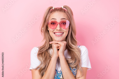 Photo of pretty cute cheerful woman with ponytails dressed flower print overall in sunglass smiling isolated on pink color background