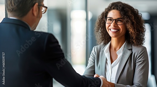 Happy mature Latin business woman manager or lawyer handshaking client at office meeting. Smiling professional businesswoman and businessman shake having partnership agreement with handshake photo