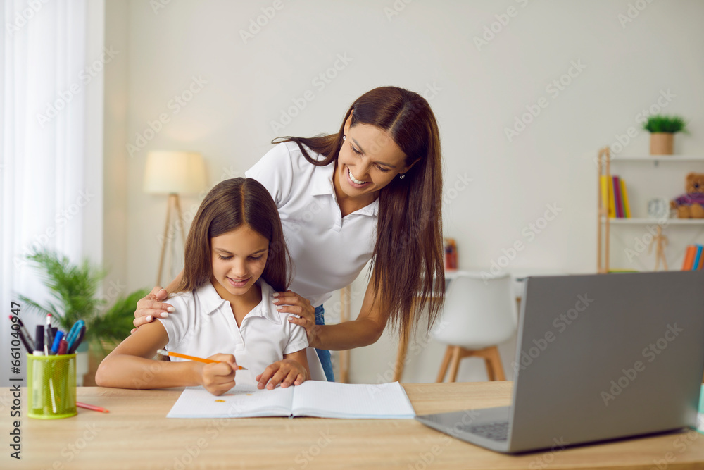 Happy, cheerful family doing homework together. Supportive, smiling mother helping her daughter while she is sitting at desk and doing creative school assignment. Children and education concept Happy, cheerful family doing homework together. Supportive, smiling mother helping her daughter while she is sitting at desk and doing creative school assignment. Children and education concept