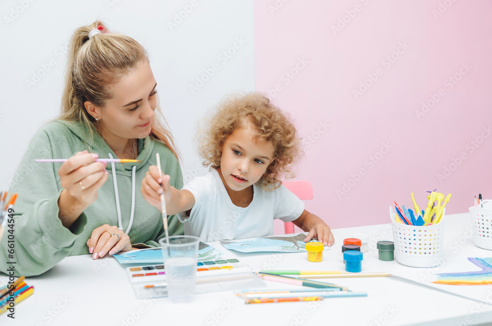 mother and child draw. daughter is engaged in creativity. mother and daughter paint. mother and child draw. daughter is engaged in creativity. mother and daughter paint.