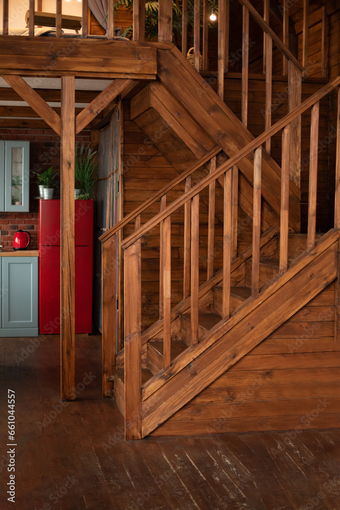 Wooden Stairway goes up. Country wooden house is spacious on two levels. Room with wooden stairway leading to second floor of modern flat. Modern staircase with wooden steps in flat. Wooden Stairway goes up. Country wooden house is spacious on two levels. Room with wooden stairway leading to second floor of modern flat. Modern staircase with wooden steps in flat.