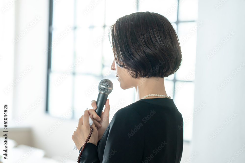 お葬式でマイクを持つ女性