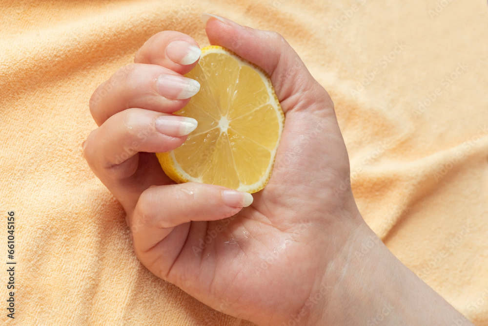 Natural long nails without polish. Hand squeezing a lemon for