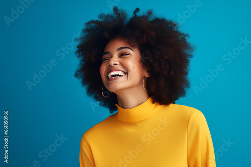 Beautiful african american woman with afro hairstyle laughing on blue background. ia generated