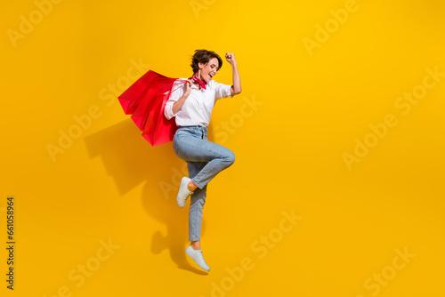 Full length photo of overjoyed funky girl raise hand fist celebrate reoice black friday sale isolated on yellow color background