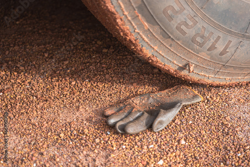 A construction worker rubber glove is placed on dirt ground under the heavy vehicle wheel road at construction worksite. Transportation accident scene concept.