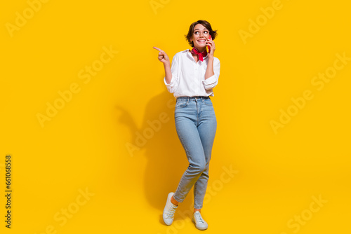 Photo of adorable lovely girl dressed trendy clothes looking up empty space recommend buy device isolated on yellow color background