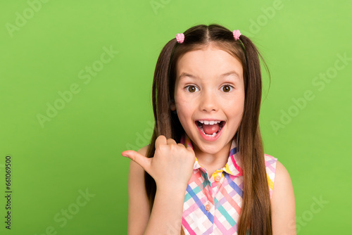 Portrait of charming astonished girl open mouth unbelievable indicate finger empty space isolated on green color background