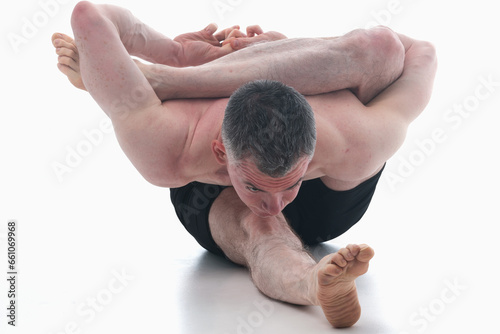 Kapilasana (Kapila pose), Ashtanga yoga  Man wearing sportswear doing Yoga exercise against white background. Black and white image. photo