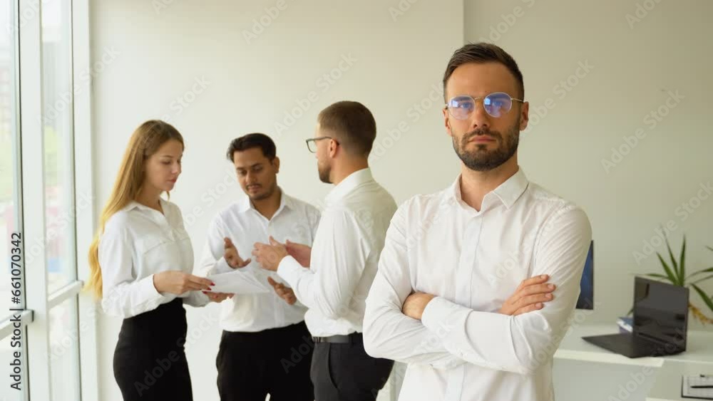 Handsome young business man standing confident in the office in front of his team