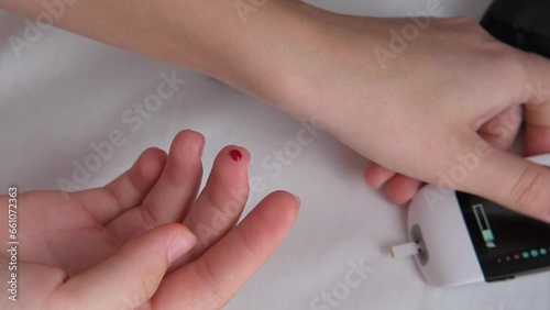 Teenager with diabetes measures blood glucose levels with a glucometer at home.