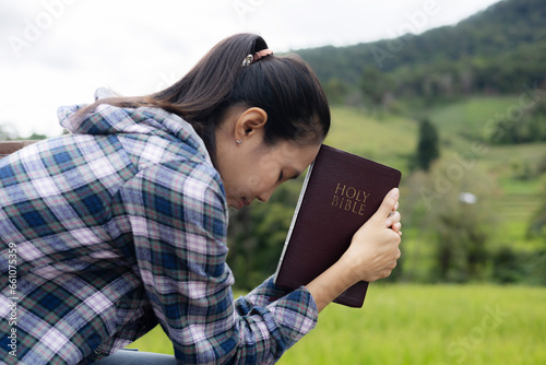 Woman praying on holy scripture in field during beautiful sunris