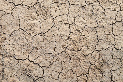 Top view of abstract, cracked, brown earth resembling the surface of Mars or the moon, a textured topography portraying the beauty of desolation