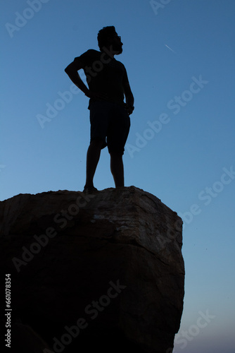 single man standing on the top of the rock or mountain and view the sunset with blue sky on the background