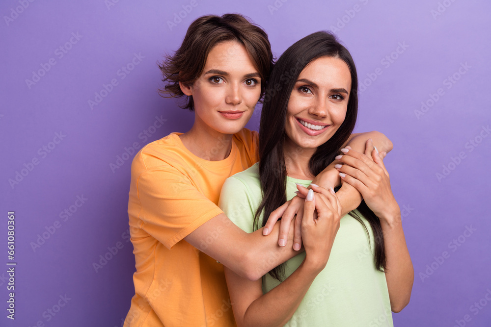 Photo of cheerful charming ladies wear t-shirts smiling embracing isolated violet color background