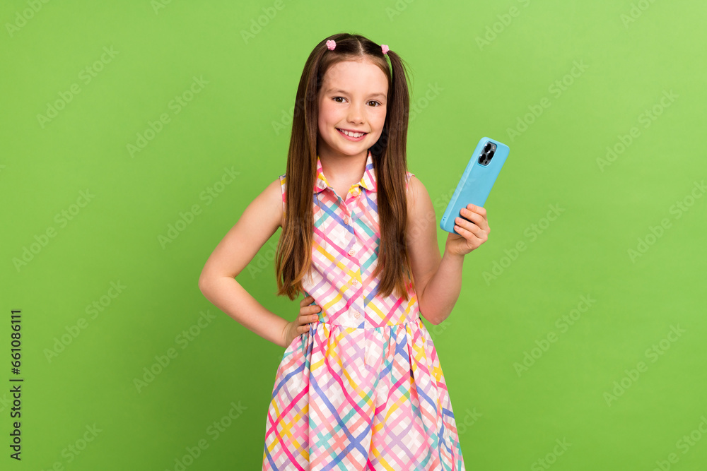 Portrait of little lovely person put arm waist hold smart phone chatting isolated on green color background Portrait of little lovely person put arm waist hold smart phone chatting isolated on green color background