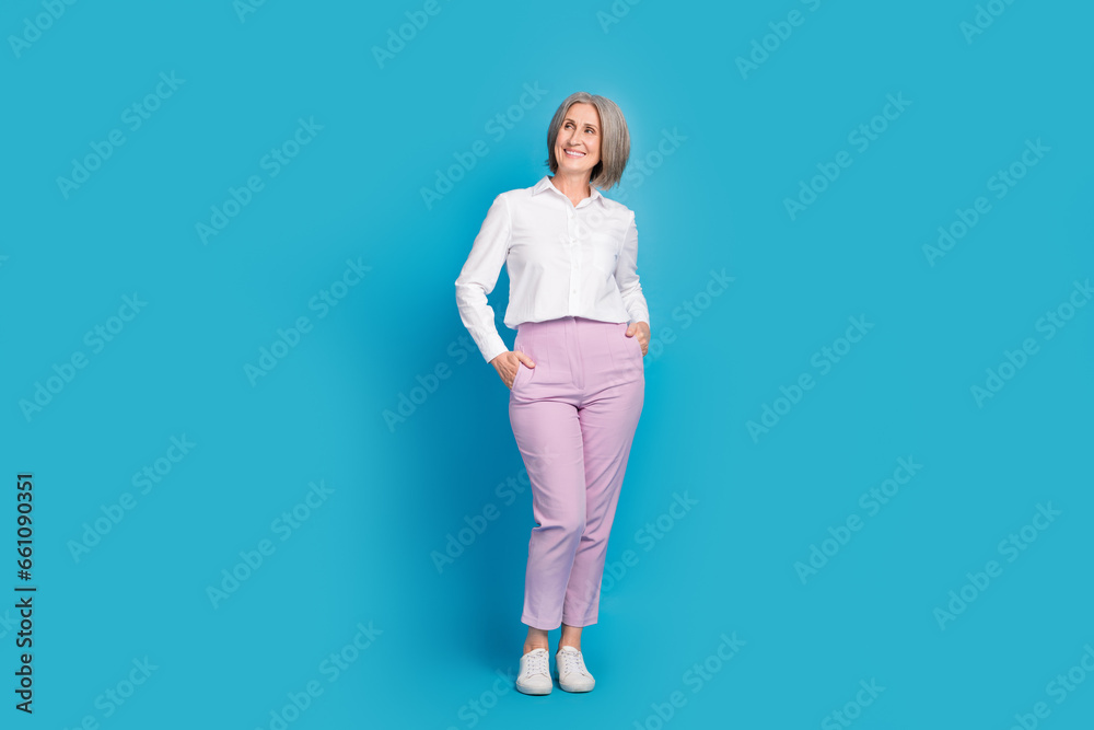 Full body portrait of pretty creative aged lady put arms pockets look empty space brainstorming isolated on blue color background Full body portrait of pretty creative aged lady put arms pockets look empty space brainstorming isolated on blue color background