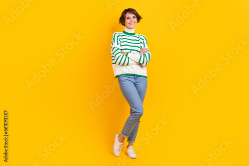Full body length photo of young charming lady wearing striped pullover jeans style folded arms posing model isolated on yellow background
