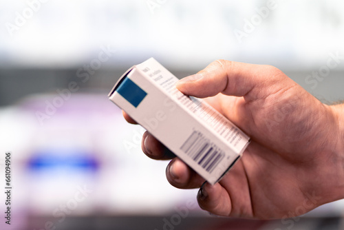 Pharmacy, medicine store and drug shop. Box of medical product. Pharmacist or customer holding paracetamol, ibuprofen or painkiller medication in hand in drugstore. Man reading information label.