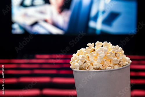 Movies and popcorn. Pop corn at cinema. Family film night concept. Action or romantic comedy entertainment on screen. Dark theater with red seats. Salty snack in bucket or box. Spectator or critic pov