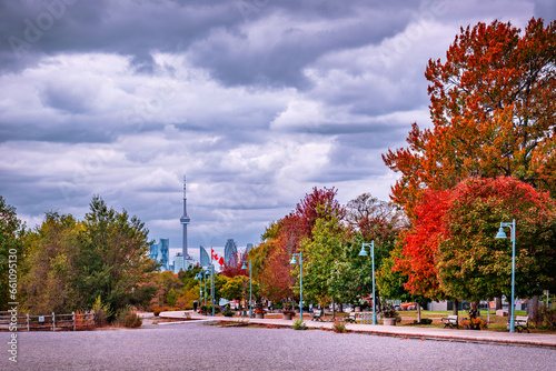 autumn in the city: fall colors along a wooden boardwalk with a big city skyline and canadain flag in the background room for text photo