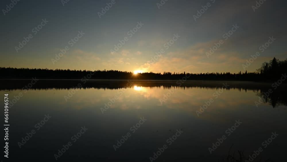 Time lapse of the sun rising above a calm lake that is surrounded by a forest of spruce and pine trees. A fine foggy mist blows across the lake.
Time lapse of the sun rising above a calm lake that is surrounded by a forest of spruce and pine trees. A fine foggy mist blows across the lake.