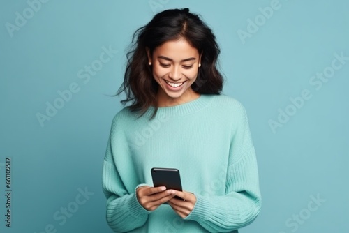 attractive young asian female student texting friend, holding smartphone