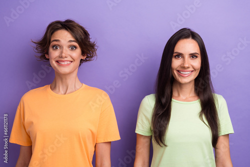 Photo of excited funky ladies wear t-shirts smiling showing white teeth isolated violet color background