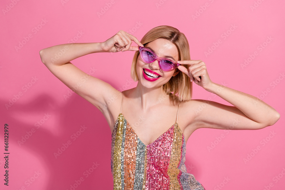 Photo of positive cheerful lovely woman with bob hairdo dressed shiny clothes hands touching sunglass isolated on pink color background