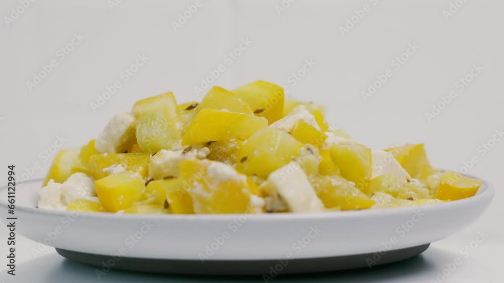 A white plate with a prepared dish of zucchini and feta cheese is spinning on the turntable. Close-up, presentation. A white plate with a prepared dish of zucchini and feta cheese is spinning on the turntable. Close-up, presentation.
