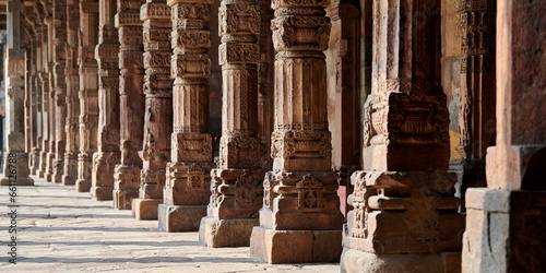 Stone columns with decorative bas relief of Qutb complex in South Delhi, India, close up pillars in ancient ruins of mosque landmark, popular touristic spot in New Delhi, ancient indian architecture photo