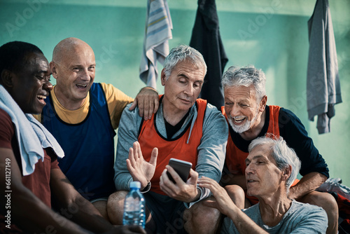 Diverse group of seniors taking using a smartphone in the locker room after a football match © Geber86