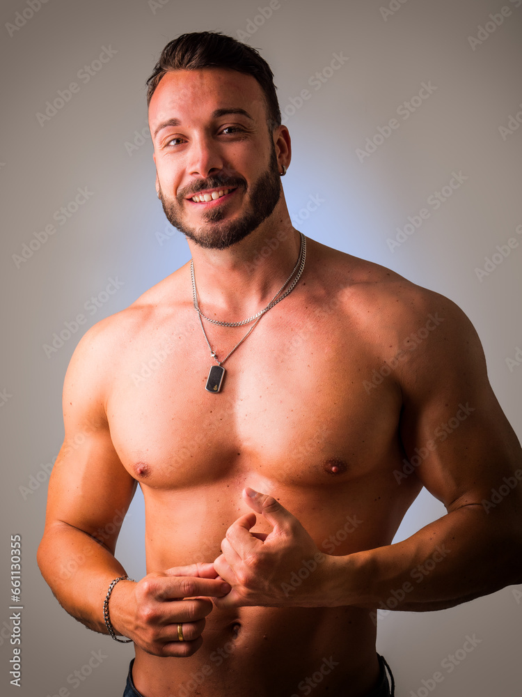 A shirtless man posing for a picture. Photo of a muscular man striking a pose for a captivating portrait in studio, smiling to the camera