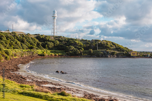 Photograph of the Currie Lighthouse on a hill as viewed from across the bay on King Island in the Bass Strait of Tasmania in Australia