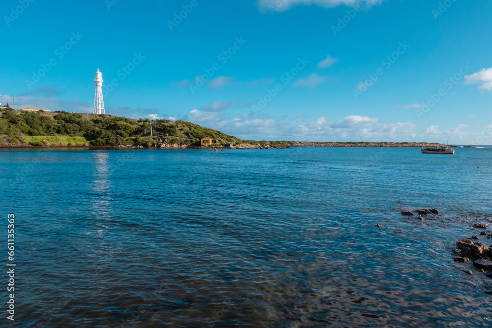 Photograph of the Currie Lighthouse on a hill as viewed from across the bay on King Island in the Bass Strait of Tasmania in Australia