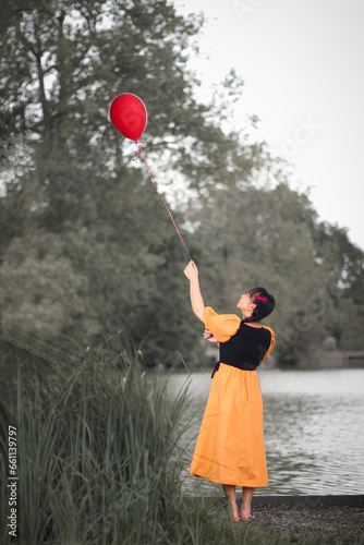 Beautiful lady outdoors with red ballon during autumn/fall