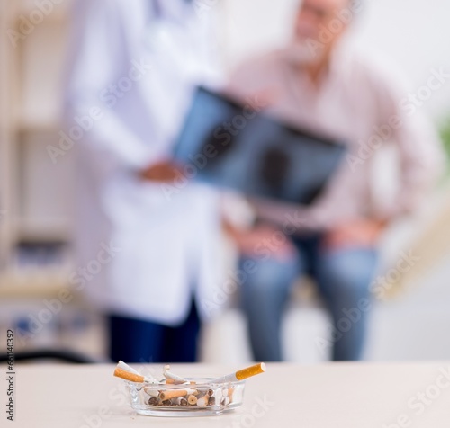 Young male doctor and old patient in antismoking concept photo