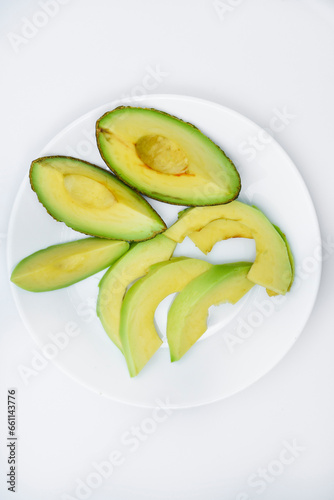 Sliced slices of green avocado in the kitchen. Delicious avocado close-up on dishes.