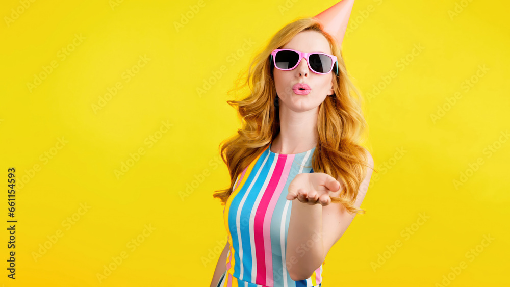 Wink, flirt and hipster woman sending air kiss and happy excited smiling. Fashionable lady blowing a kiss with confidence flirty emotion for cosmetics makeup, trendy outfit in studio yellow background - obrazy, fototapety, plakaty 